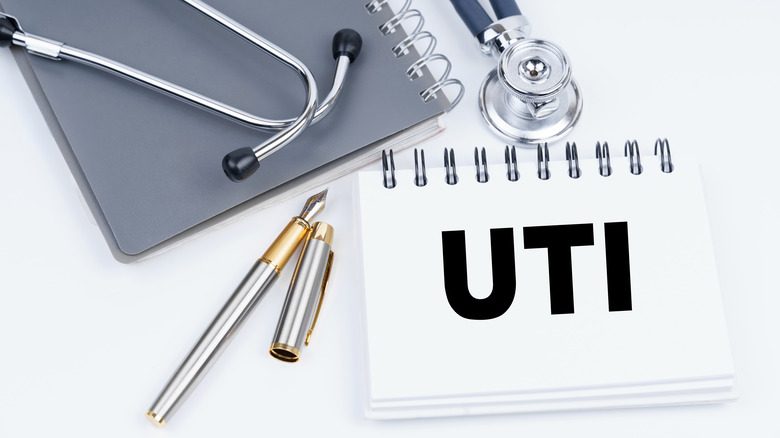 Медицинские предметы на столе, включая ручку, стетоскоп, блокнот и табличку с надписью UTI