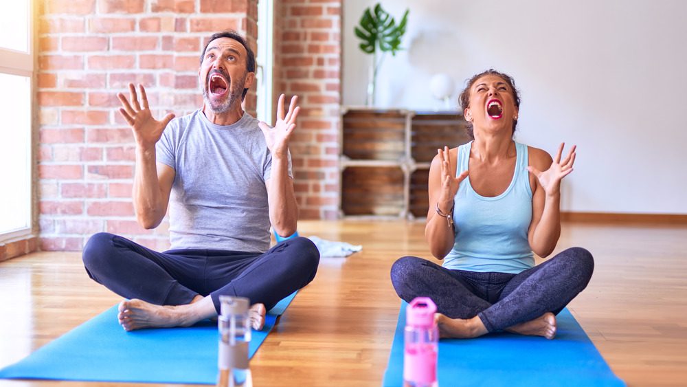Два человека в ярости кричат на ковриках для йоги