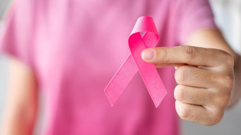 женщина держит розовую ленту в поддержку рака груди