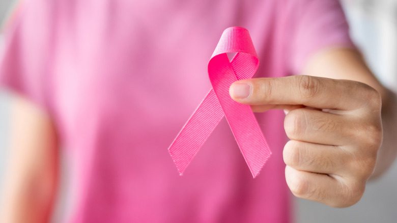 женщина держит розовую ленту в поддержку борьбы с раком груди