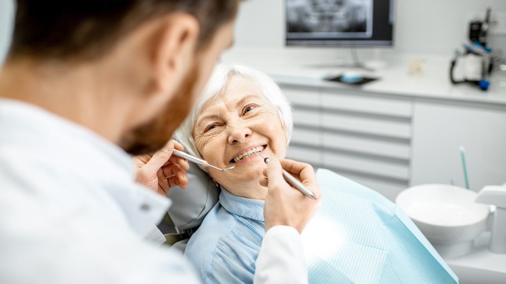 Улыбающаяся пожилая женщина в кресле стоматолога