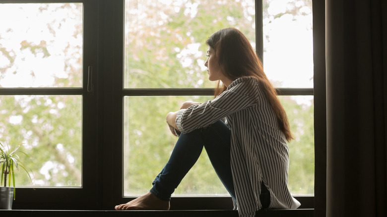 Женщина в одиночестве смотрит в окно