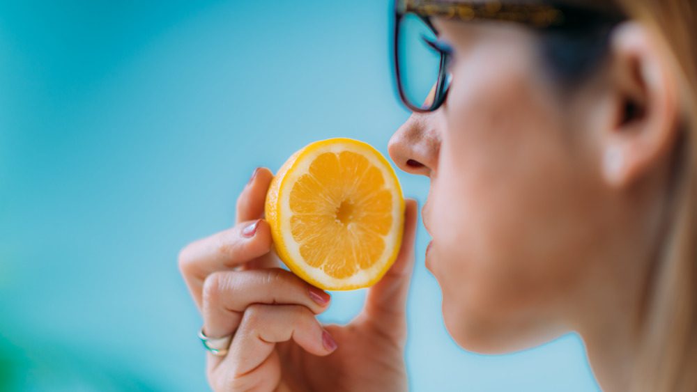 Женщина нюхает половинку апельсина