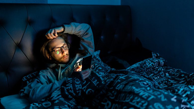 мужчина проверяет телефон в постели