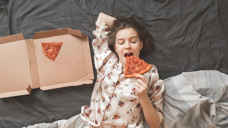 женщина ест пиццу в постели