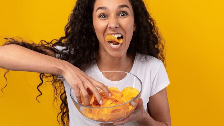 счастливая женщина ест чипсы