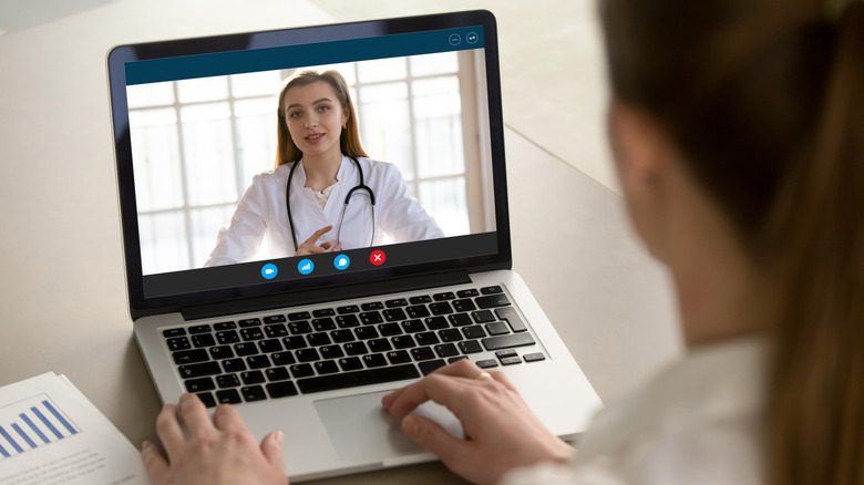 Женщина с хвостиком смотрит на своего врача на экране ноутбука во время телемедицинского приема