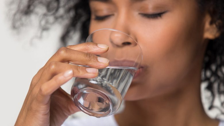 чернокожая женщина пьет стакан воды утром