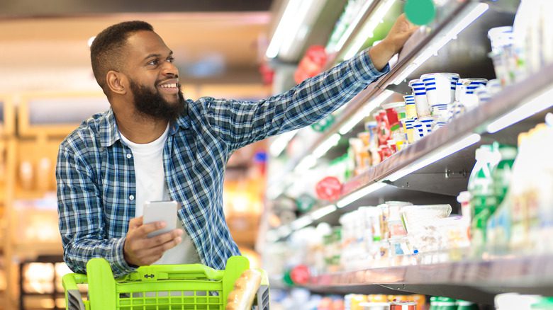 Мужчина в продуктовом магазине выбирает продукты