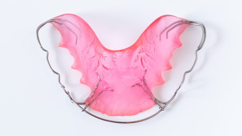 Розовый зубной фиксатор на белом фоне