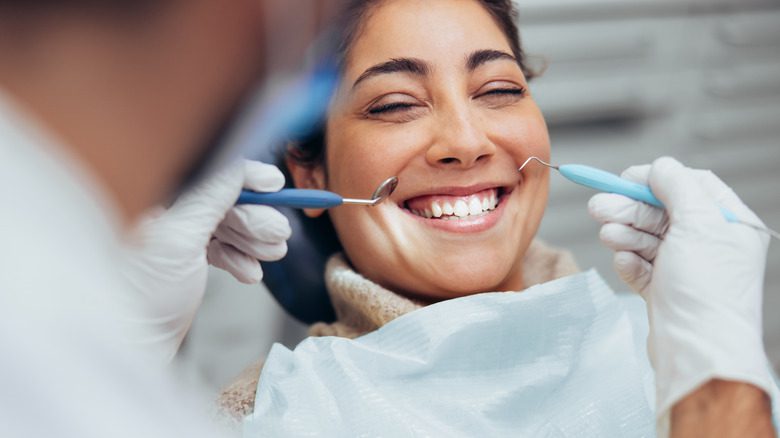 Женщина в кресле стоматолога осматривает зубы