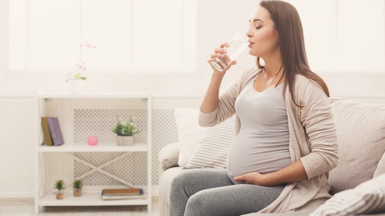 беременная женщина пьет стакан воды