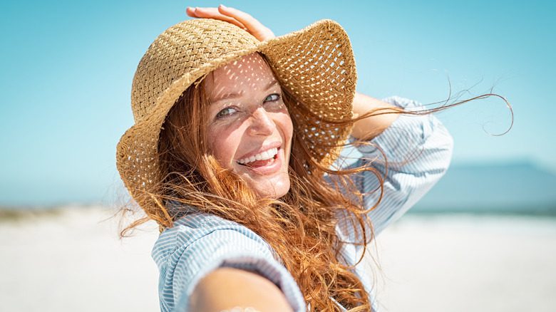 Женщина улыбается в соломенной шляпе на пляже