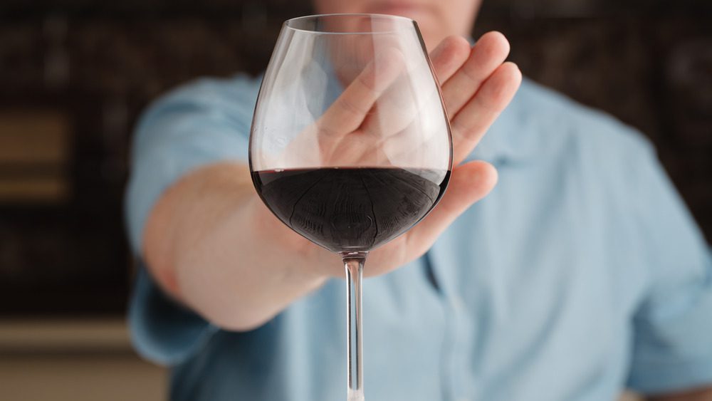 Человек отказывается от бокала вина с поднятой рукой