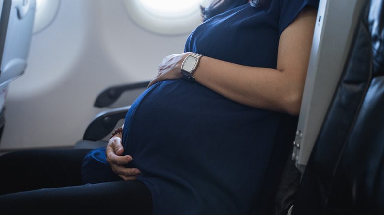 беременная женщина сидит в кресле самолета