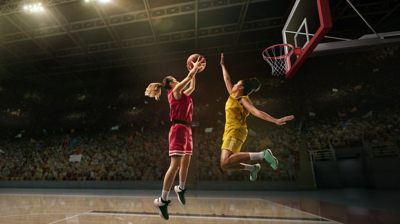 Баскетболисты борются за мяч во время воздушного прыжка на площадке
