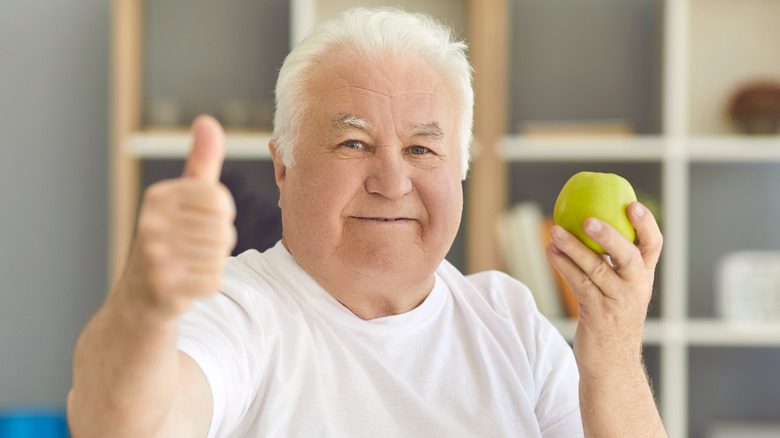 пожилой человек держит яблоко