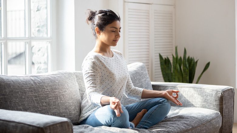 Женщина медитирует на диване