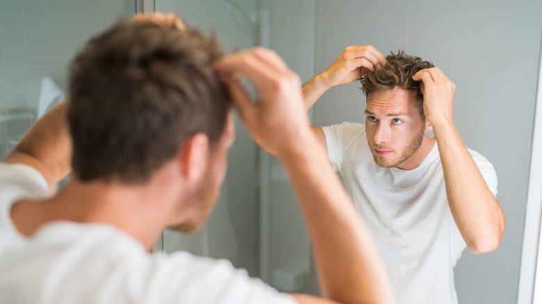 Мужчина, смотрящий в зеркало из-за потери волос
