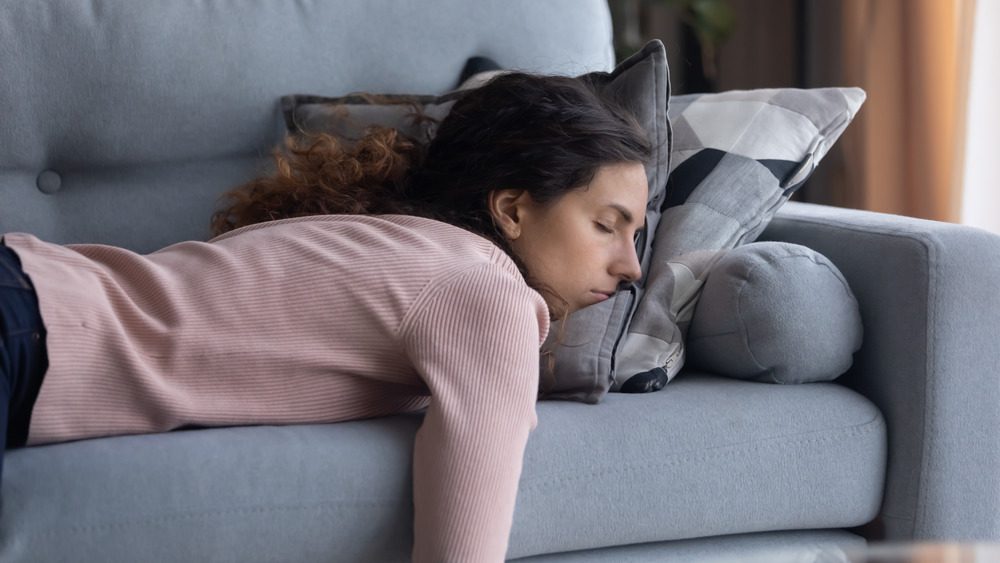 Измотанная стрессом женщина спит лицом вниз на диване