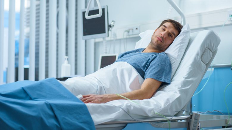 Мужчина лежит на больничной койке, восстанавливаясь после операции