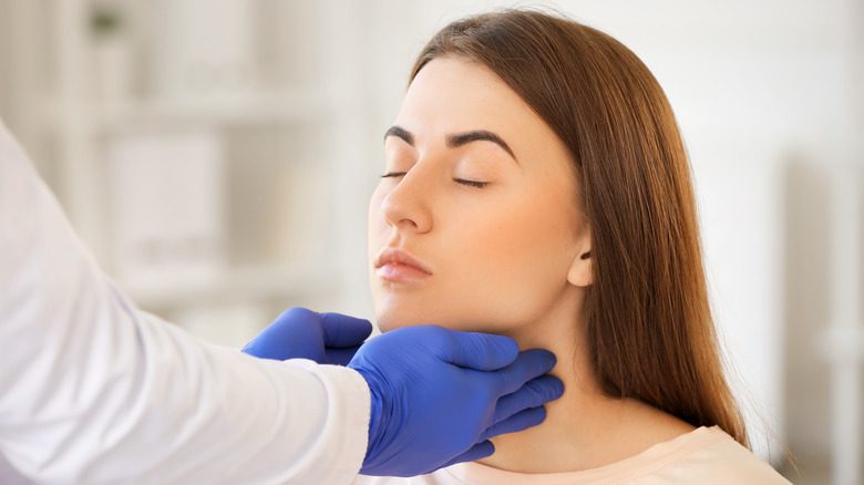 врач проверяет щитовидную железу женщины