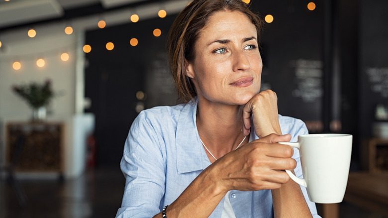 Женщина держит кружку с кофе в кафе