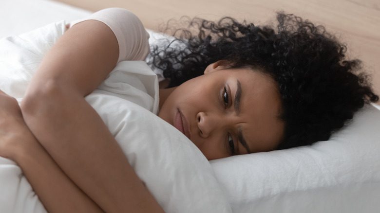 Женщина в состоянии стресса лежит в постели