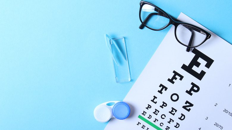 Диаграмма для проверки зрения, а также очки и линзы для коррекции зрения на синем фоне