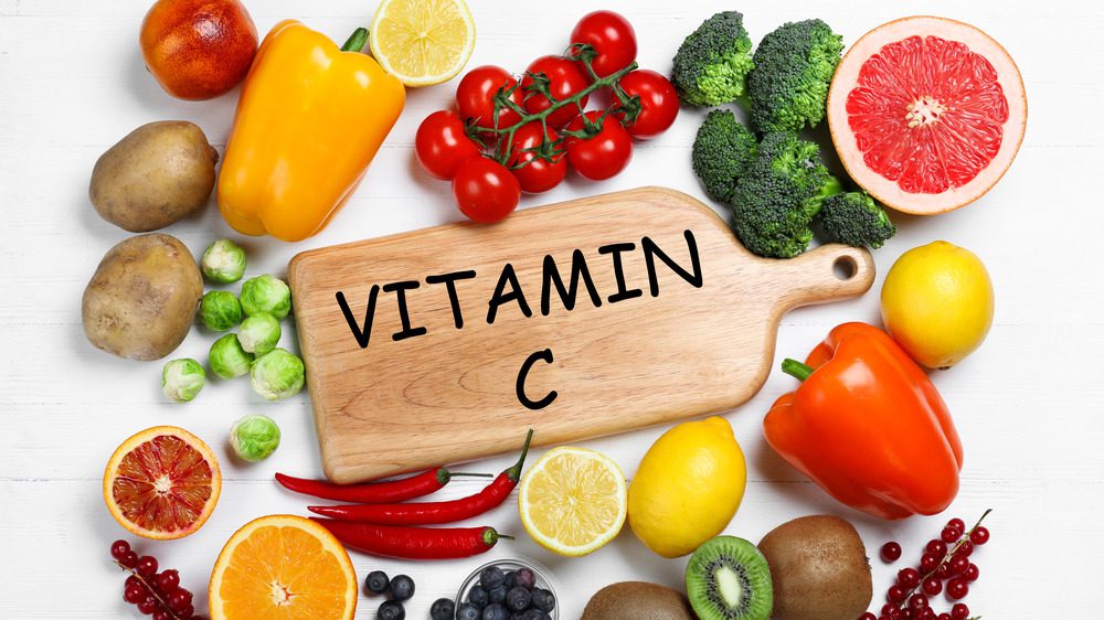витамин с на доске в окружении овощей и фруктов