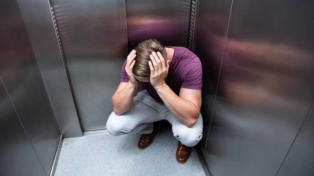 Мужчина в лифте с руками на голове