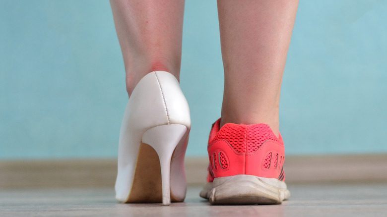 Крупный план пары ног, обутых в туфли на высоком каблуке и розовые кроссовки