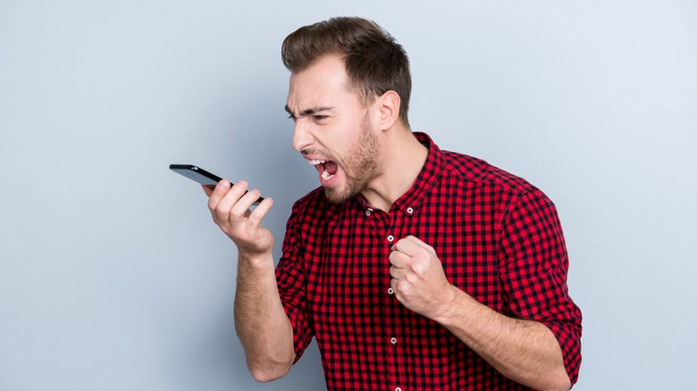 Раздраженный мужчина кричит в свой мобильный телефон